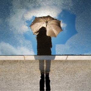 reflection of girl holding umbrella from puddle